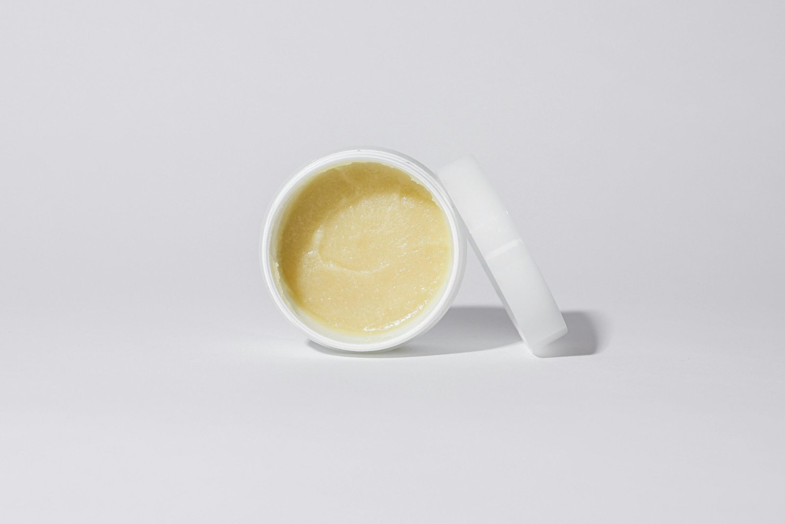 Clean and simple close-up of a cosmetic cream in a white container against a neutral background.