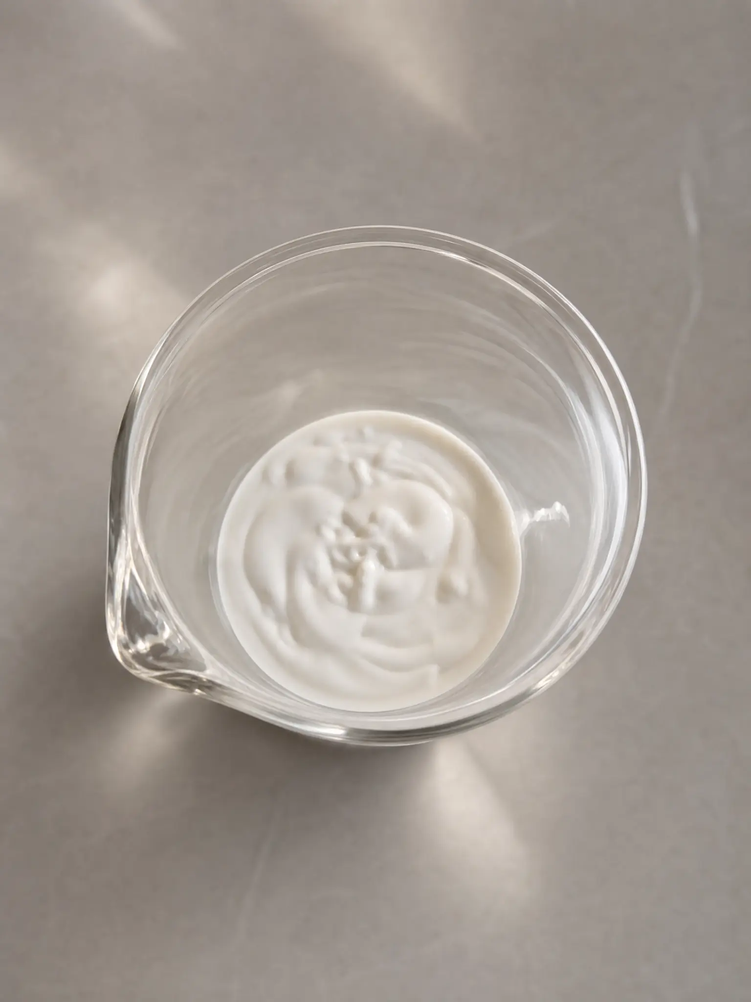 A smooth eye-cream texture shown in a clear beaker during confidential sample review